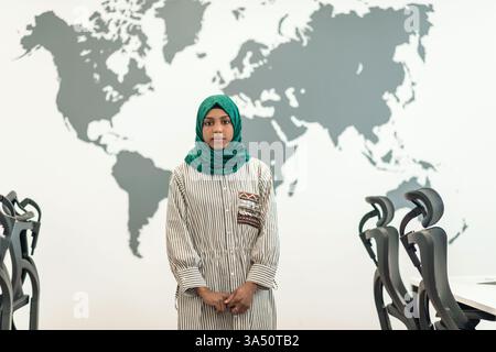 Portrait of a Muslim female software developer wearing a green hijab in a modern open-plan startup office. This clean, professional image highlights diversity in tech and female leadership. Suitable for technology, software development, and inclusive workplace visuals. Stock Photo