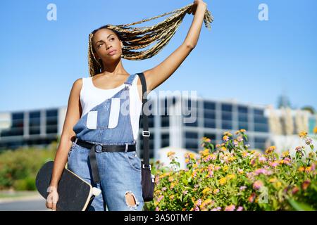 Beautiful young Black woman with braided hairstyle posing outdoors. Colorful, stylish portrait suitable for fashion, hair care and beauty campaigns. Great for features on African-inspired style and urban culture. Stock Photo