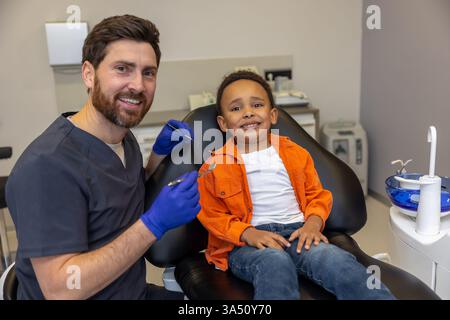 Dentist and patient share a happy smile after treatment. Indoor dental clinic setting with a positive, healthy vibe. Ideal for healthcare and dental care communications. Stock Photo