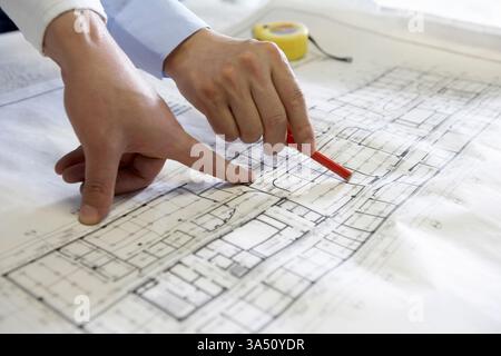 Chinese architects review blueprints and point at building plans in a professional setting. This scene highlights teamwork, planning, and architectural expertise. Ideal for construction, design, and office-related campaigns. Stock Photo