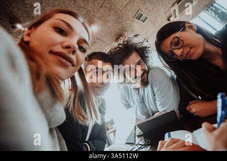 Enterprising young entrepreneurs sit in a modern office using laptops and devices. A diverse, multinational team conveys collaboration and innovation in a contemporary corporate setting. Great for startup, business, and team-building visuals. Stock Photo