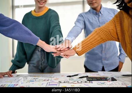 Close?up of hands joining together in a team meeting, symbolizing teamwork and collaboration. The scene features a diverse group in a coworking or office setting focused on partnership. Great for startup, tech, and UX design concepts. Stock Photo