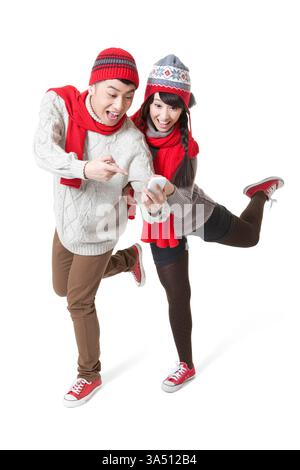 Playful young Asian couple using smartphones during Chinese New Year celebrations. The festive mood and modern tech make this image ideal for holiday campaigns and social media content. Copy space and wide composition support messaging and branding. Stock Photo