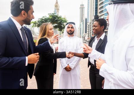 Diverse group of professionals walking outdoors in the UAE and discussing business. Useful for teamwork, multinational enterprise, and Middle East business campaigns. Stock Photo