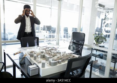 Busy Black businessman in a modern office, looking focused and thoughtful. Great for corporate communication, leadership, and business lifestyle visuals. Stock Photo