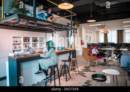 Group of casual multiethnic businesspeople taking a break in a modern coworking area. A relaxed moment that showcases teamwork and diverse professionals in a contemporary workspace. Great for articles on company culture, flexible work environments, and open offices. Stock Photo