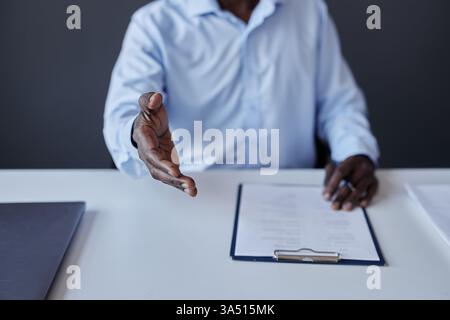 Close-up of a recruiter extending a handshake toward the camera with copy space. Ideal for recruitment, HR, and hiring imagery in a corporate context. Stock Photo