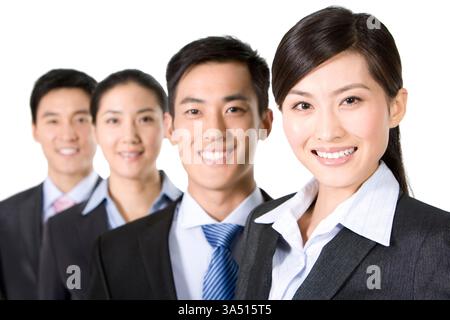 Four Asian professionals, including Chinese businessmen and businesswomen, stand together in a studio against a white background. This cheerful group portrait conveys teamwork, cooperation and positive business relationships. Ideal for corporate communications, teamwork campaigns and partnership themes. Stock Photo