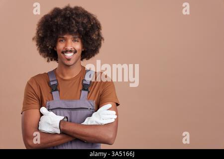 Friendly African man in a carpentry uniform poses in a studio with a welcoming smile. Perfect for construction, woodworking, and professional lifestyle projects featuring a tradesperson. Stock Photo