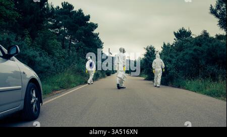 Medical specialists in full protective suits walk along a road, signaling frontline response during a health crisis. The scene emphasizes safety, infection control, and emergency readiness with masks and gloves. Suitable for Covid-19, epidemic, and healthcare communications. Stock Photo