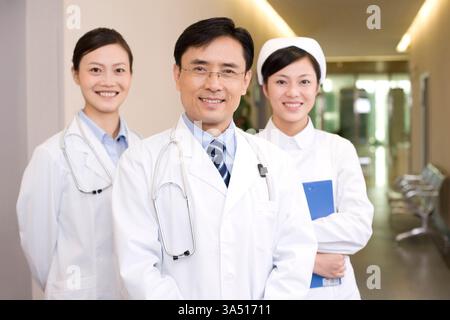Portrait of a professional Chinese medical team in a hospital setting. They stand in a clinical corridor wearing lab coats, radiating confidence and leadership. This image suits features about healthcare professionals, teamwork and hospital care in Beijing. Stock Photo