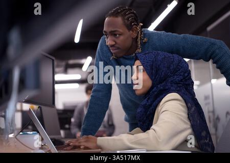 Focused Black business people discuss a project at a desk with a desktop computer in a modern office. The scene communicates teamwork, technology, and a productive, corporate environment. Stock Photo