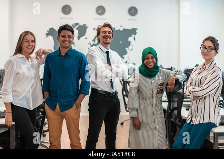 Portrait of a diverse, excited software development team in a modern startup office. They stand together, looking at the camera with energy and smiles. Perfect for stories about teamwork, innovation, and multicultural workplaces in tech. Stock Photo