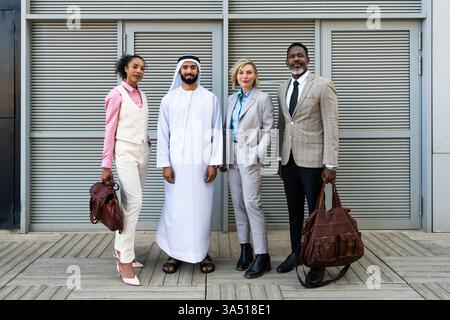 Group of multiethnic professionals, including an Emirati businessman, bonding outdoors in an urban setting. Great for corporate teamwork, international business, and diversity in the workplace. Stock Photo