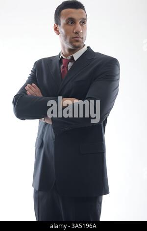 Senior Middle Eastern businessman stands in a studio, wearing a suit and looking away from the camera. A strong corporate portrait suitable for leadership, business success, and executive topics. Ideal for professional or corporate communications content. Stock Photo