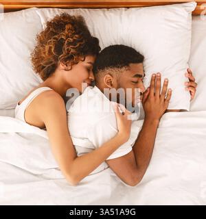 Afro couple hugging while sleeping together in bed, top view Stock ...