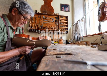 Violin maker at work in a traditional Italian workshop. Perfect for features on craftsmanship, handmade instruments, and artisanal design. Stock Photo