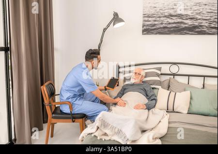 Qualified medical practitioner examines an elderly patient during a home visit. The intimate indoor scene emphasizes compassionate, in-home healthcare. Ideal for healthcare services, elder care, and patient care themes. Stock Photo