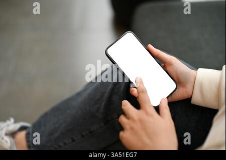 Close-up of a woman in casual clothes using a smartphone in a cafe, with a white screen mockup. The image is ideal for apps, websites, and mobile content focused on digital communication. Great for social media and everyday connectivity themes. Stock Photo