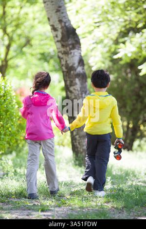 Happy Chinese children holding hands running in woods Stock Photo - Alamy