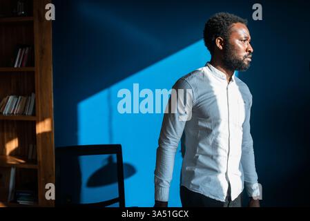 Serious Black man looking away standing in office on sunny day Stock Photo