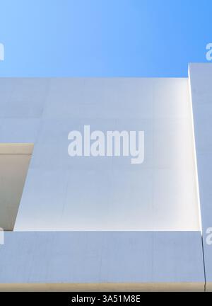 Almost abstract detail of a white facade made of concrete poured in place and photographed against blue sky on a sunny bright day. Warsaw, Poland. Stock Photo