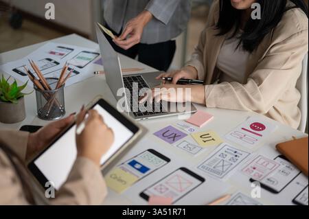Busy, creative graphic design team collaborates in a modern office, brainstorming ideas for a new project. Focused on UX and UI concepts, colleagues plan the development and design of the application. Stock Photo