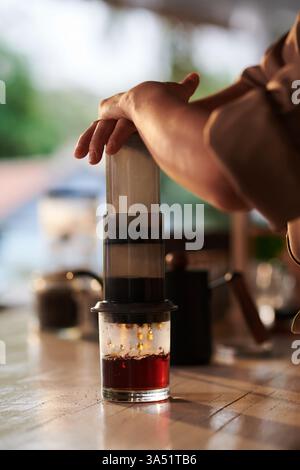 Asian female barista prepares coffee using an Aeropress in a modern cafe. A candid workplace scene that suits coffee shops, beverages, and hospitality marketing. Great for cafe menus, lifestyle blogs, or product promotions. Stock Photo