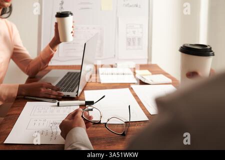 Marketing manager and UI designer discuss mobile app layouts and wireframes during a focused meeting in the office. Ideal for topics on UX design, UI development, collaboration, and digital product planning. Stock Photo