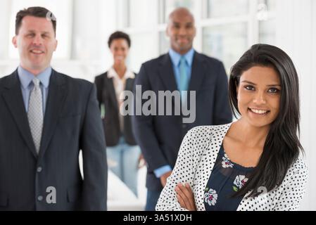 Diverse group of four professionals in a light, airy city office. Two men and two women are featured, suggesting teamwork and collaboration in a corporate setting. Ideal for business, teamwork, and workplace diversity imagery. Stock Photo