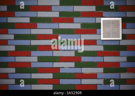 A facade made of colourful clinker bricks with a ventilation grille in the wall Stock Photo