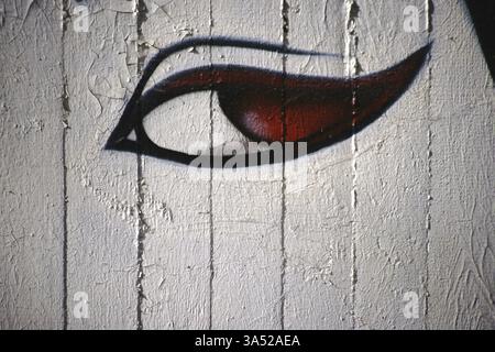 A spray-painted or painted woman's eye with red pupils on a concrete wall Stock Photo