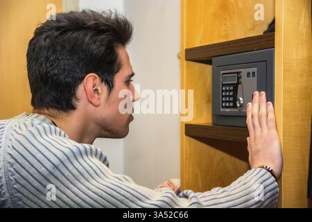 Young handsome man using a small vault or safe in his home Stock Photo