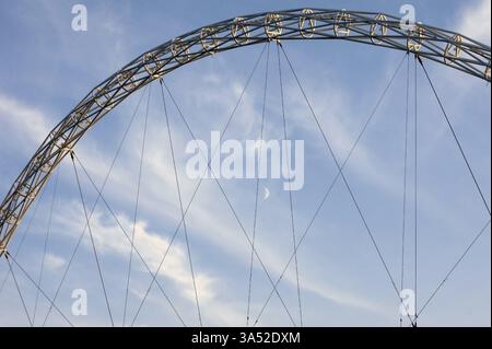 London, United Kingdom - November 28, 2014: The architecturally striking arch of Wembley Stadium with a crescent moon and feathery clouds in the backg Stock Photo
