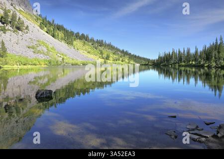 The majestic mountains and pine forests are reflected in the smooth water. A quiet lake in the mountains of California Stock Photo