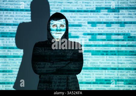 Hacker with projection of programming code in dark room Stock Photo
