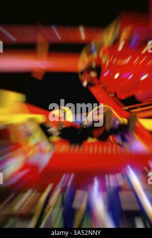 The abstract silhouettes of seats and visitors on a rotating carousel Stock Photo