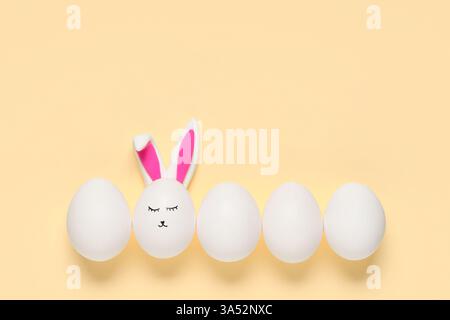 Easter eggs with drawn face and bunny ears on beige background Stock Photo
