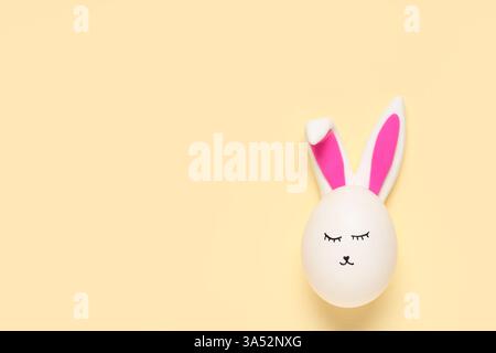 Easter eggs with drawn face and bunny ears on beige background Stock Photo