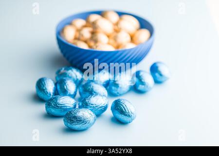 Chocolate easter eggs wrapped in blue colored foil on a blue background. Stock Photo