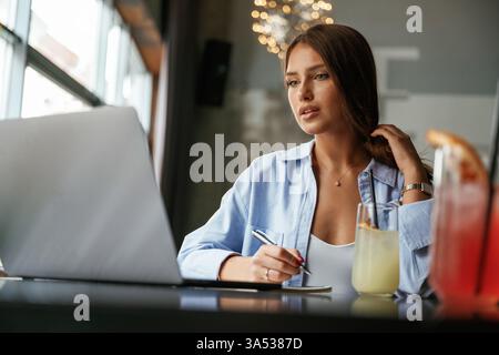 Focused at work. Beautiful woman with laptop is in the bar. Stock Photo