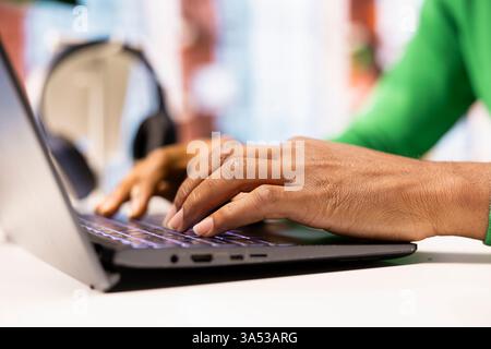 Freelancer at home office desk typing on laptop keyboard to compose social media posts, producing content. Close up of remote worker using notebook to monitor company social media engagement Stock Photo
