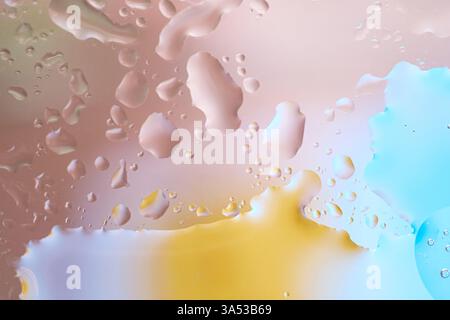 Transparent drops of water and oil create a beautiful pattern on a blue and yellow beige background. Macro shot of liquid texture with reflections and Stock Photo