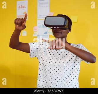 Woman using VR headset interacting with virtual interface in modern office Stock Photo