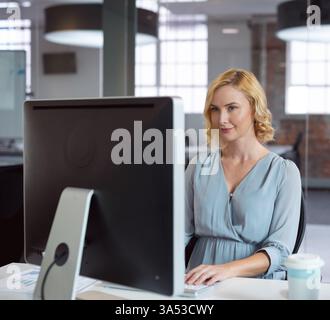 Professional woman working on desktop computer in modern office, focused and engaged Stock Photo