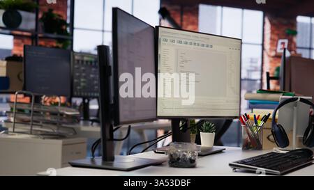 Advanced AI algorithms running on computer monitors in empty startup workspace deploying machine learning models. Coding platform on PC screens in Silicon Valley office, close up shot Stock Photo