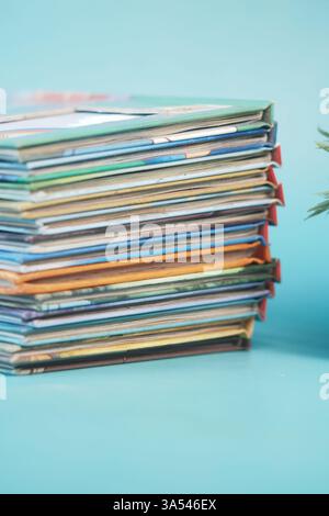Stack of colorful magazines resting on a light blue surface Stock Photo