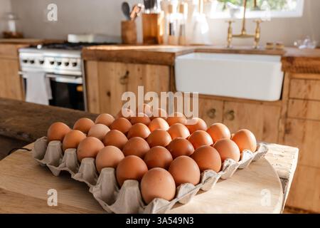 Sunlight streaming on rustic kitchen counter with fresh brown eggs in carton Stock Photo
