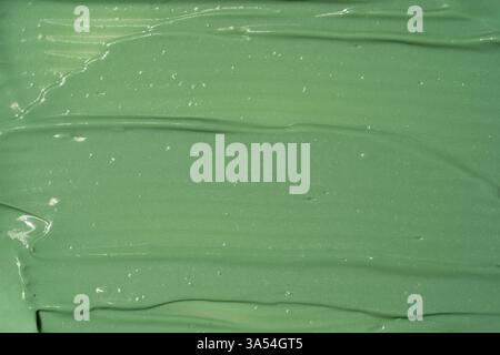 Green cosmetic clay facial mask, cream, body scrub texture close up, top view. Abstract background with brush strokes. Stock Photo
