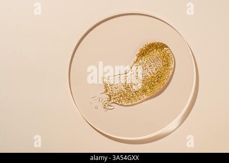 Liquid gel gold. transparent gel liquid with golden glitter In a Petri dish on beige background. Laboratory research of cosmetics, gel, medicine. Chem Stock Photo